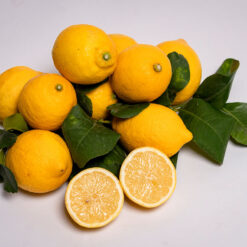 Un insieme di limoni con accanto foglie di albero di limone.