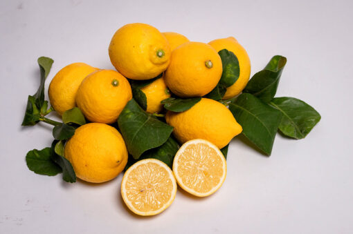 Un insieme di limoni con accanto foglie di albero di limone.